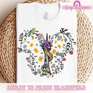 May include: White t-shirt featuring a colorful graphic of a tower with Rapunzel's hair, surrounded by flowers and floating lanterns. A green chameleon sits on the floral design. The text "READY TO PRESS TRANSFERS" is at the bottom.
