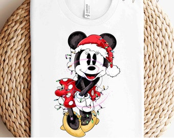 Puede incluir: Camiseta blanca con un diseño de dibujos animados de Minnie Mouse. Minnie lleva un vestido rojo de lunares y un gorro de Papá Noel, con luces navideñas. El texto "READY TO PRESS TRANSFERS" está en la parte inferior.