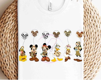 Könnte beinhalten: Ein weißes T-Shirt mit einem Design von Mickey Mouse, Minnie Mouse, Donald Duck, Goofy und Pluto, die in Safari-Outfits gekleidet sind. Jeder Charakter hält einen Ballon mit einem anderen Tierdruck. Der Text "READY TO PRESS TRANSFERS" befindet sich am unteren Rand des Shirts.