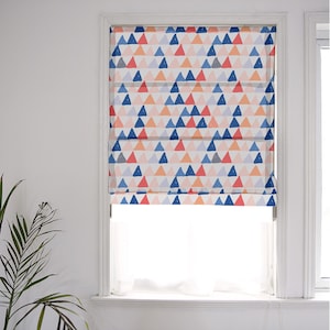 Peut inclure: Un store romain blanc avec un motif géométrique de triangles bleus, roses et oranges. Le store est partiellement relevé, révélant une fenêtre blanche derrière.