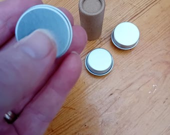 May include: Three silver metal lids for small containers and a cardboard tube.