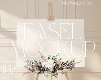 Peut inclure: Une scène de maquette stylisée avec un chevalet blanc portant le texte "EASEL MOCKUP" et "DIN A4 RATIO". Le chevalet soutient un panneau blanc vierge, orné d'une composition florale de feuillage blanc, bordeaux et vert.