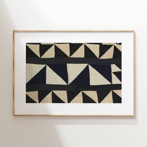 May include: A framed print of a geometric pattern in black, white, and beige. The pattern is made up of triangles arranged in a repeating pattern.