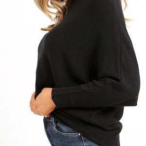 May include: A black long-sleeved sweater with a relaxed fit and a mock neck.