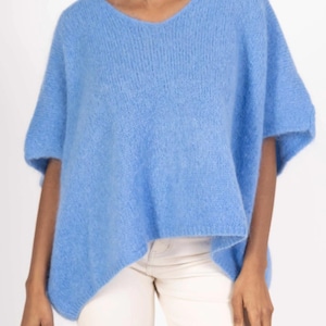 Puede incluir: Un suéter azul claro, peludo, de manga corta con cuello en V.