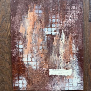May include: Abstract painting with a textured surface in shades of brown, orange, and white. The artwork features a grid-like pattern and a small paper with text that reads "If you are outgrowing who you've been, you are right on schedule. Keep working."