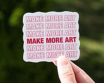 Può includere: Etichetta bianca con la frase "MAKE MORE ART" ripetuta sei volte in testo rosso.