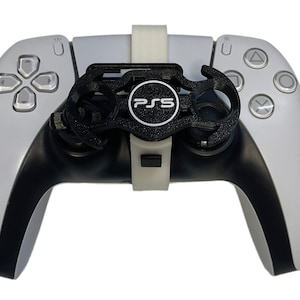 Op de afbeelding: Een zwart-witte PlayStation 5-controller met een zwart-witte gripbevestiging. De gripbevestiging heeft het PlayStation-logo erop.