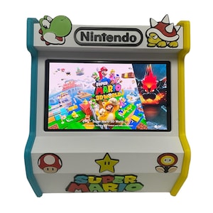 May include: A white tabletop arcade cabinet featuring a Nintendo logo, Yoshi, and a Spiny shell at the top. The screen displays the Super Mario 3D World game interface. The base is decorated with a mushroom, a star, a fire flower, and a Super Mario logo.
