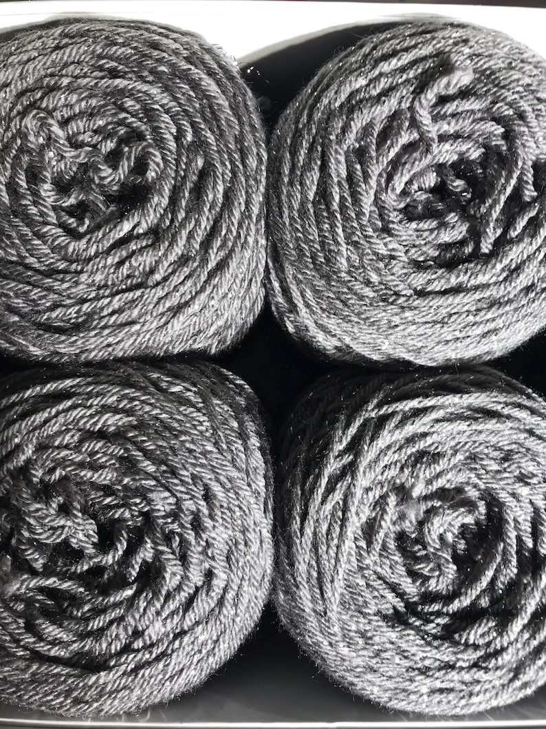 May include: Four gray yarn skeins are neatly arranged, filling the frame. The yarn is tightly wound, revealing a spiral pattern. The color is a solid, medium gray, with a slight sheen. The yarn appears soft and suitable for knitting or crochet projects.