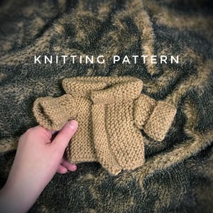 May include: Knitting pattern for a brown sweater with a turtleneck. The sweater is laying on a fuzzy brown and green surface.