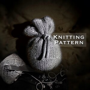 May include: A gray knitted drawstring bag with a knitted cord. The bag is sitting on a brown fabric surface. The text "Knitting Pattern" is written in white letters on a black background.