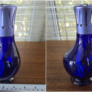 Pu&ograve; includere: Lampada profumatore in vetro blu scuro con parte superiore color argento. La lampada ha un corpo bulboso e una parte superiore decorativa con fessure verticali. La lampada &egrave; alta circa 13 cm.