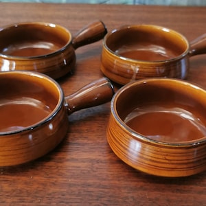 May include: Four brown ceramic soup bowls with handles. The bowls have a woodgrain pattern and a dark brown rim.