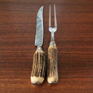 May include: A set of two vintage cutlery pieces with stag horn handles. The knife and fork have silver blades and are in good condition.