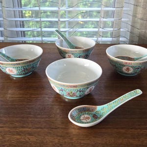 Könnte beinhalten: Set aus vier türkisfarbenen und weißen Porzellanschalen mit floralen und geometrischen Mustern und vier passenden Löffeln. Die Schalen sind in einem Kreis auf einer Holzoberfläche angeordnet.