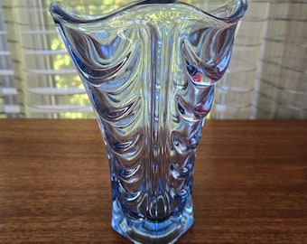 May include: A blue glass vase with a textured, wavy design. The vase has a wide mouth and a narrow base.