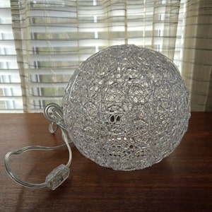 May include: A clear plastic globe light fitting with a textured surface. The light has a cord and plug.
