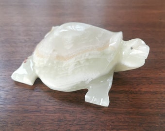 May include: A white onyx turtle figurine. The turtle is carved in a realistic style and has a smooth, polished finish.