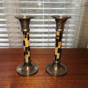 May include: A pair of silver candle holders with a black and brown checkered pattern on the base.