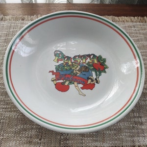 Può includere: Scodella per pasta bianca con un bordo verde e rosso. La ciotola ha un'illustrazione colorata di una donna con un nastro rosso che dice "Pasta Italiana".