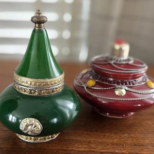 Può includere: Due contenitori decorativi, uno verde con bordi dorati e uno rosso con bordi dorati e argentati. Entrambi i contenitori hanno un coperchio a cupola.