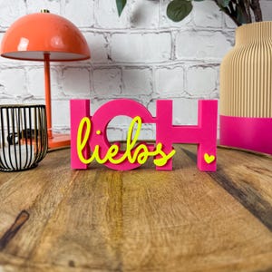 Könnte beinhalten: Ein Set aus drei Keramikbechern mit gesprenkelter, matter Oberfläche. Die Becher sind in Creme-, Hellgrau- und Dunkelgrautönen gehalten. Jeder Becher hat ein schlichtes, minimalistisches Design und einen abgerundeten Henkel.
