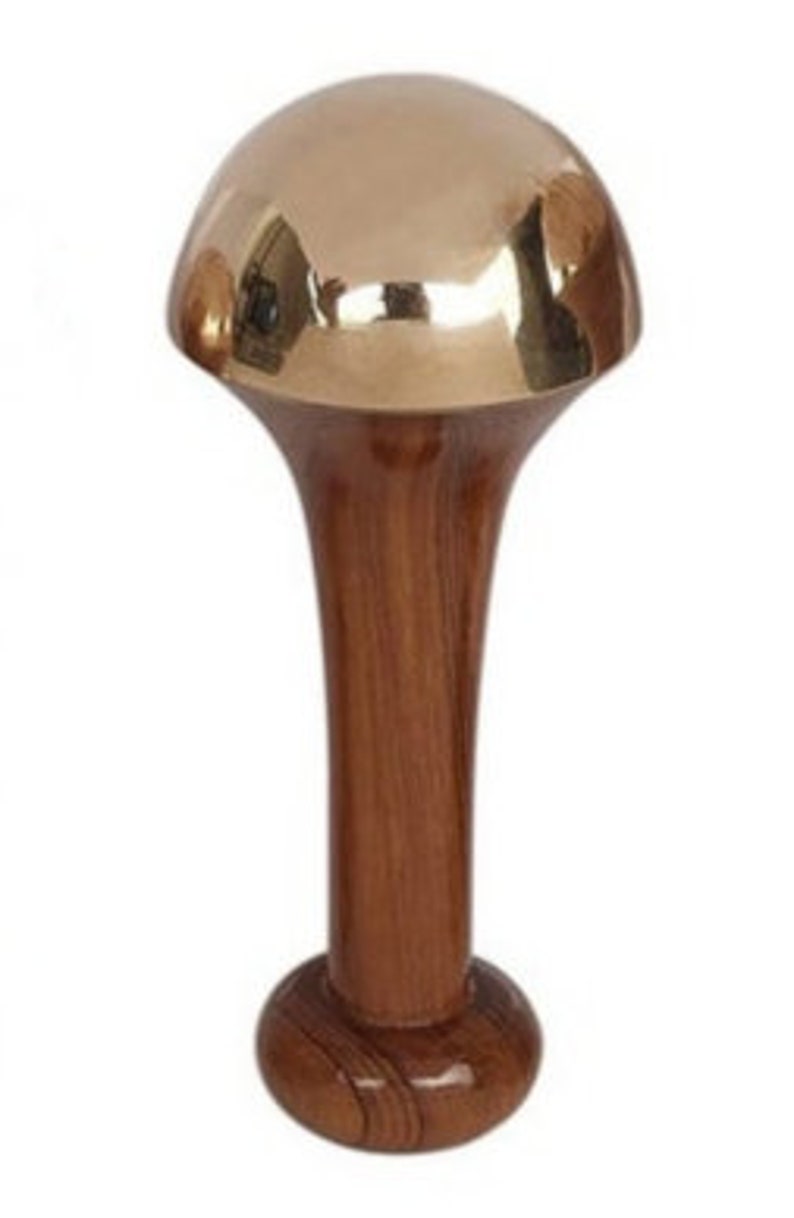 May include: A decorative walking cane with a polished brass mushroom-shaped top and a dark wood handle. The handle flares out from the base to the top, creating a unique, elegant design. The cane's base is a rounded, dark wood.