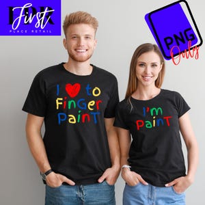 May include: Two black t-shirts with colorful text. One shirt says "I love to Finger Paint" with a red heart. The other shirt says "I'm Paint".