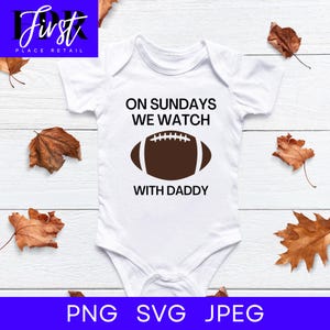 Pode incluir: Macacão branco para bebê com gráfico de futebol americano marrom e o texto "On Sundays We Watch With Daddy".