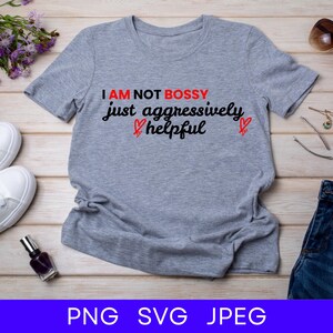 Könnte beinhalten: Graues T-Shirt mit dem Text "I am not bossy just aggressively helpful" in Schwarz mit zwei roten Herzen.