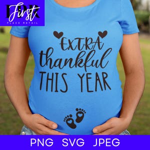 May include: A blue t-shirt with the text "EXTRA thankful THIS YEAR" and two small hearts above the text.  There are two small footprints with hearts inside on the lower center of the shirt.