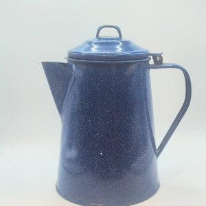 May include: A blue speckled enamelware coffee pot with a lid and handle. The pot has a spout for pouring and a loop handle on the lid. The pot is approximately 10 inches tall.