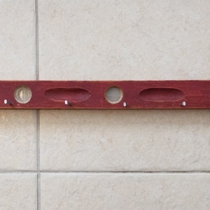May include: A red wooden level with five holes and a slightly distressed finish.