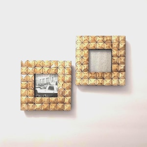 May include: Two square picture frames with a light brown wood finish and a textured, geometric pyramid pattern across the entire surface. One frame contains a black and white photograph of a city street, while the other is empty.