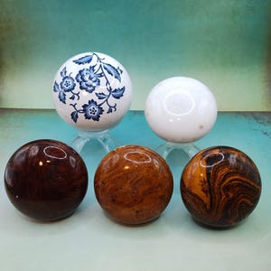 May include: Five decorative spheres, two are white with one having a blue floral design, two are brown with swirling patterns, and one is a dark brown wood.