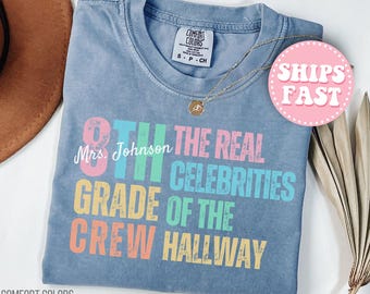 Peut inclure: T-shirt bleu Comfort Colors avec le texte "8th Grade Crew Hallway" en plusieurs couleurs. Le t-shirt porte également le texte "Mrs. Johnson" et un autocollant "Ships Fast". Un collier en or est drapé sur le t-shirt.