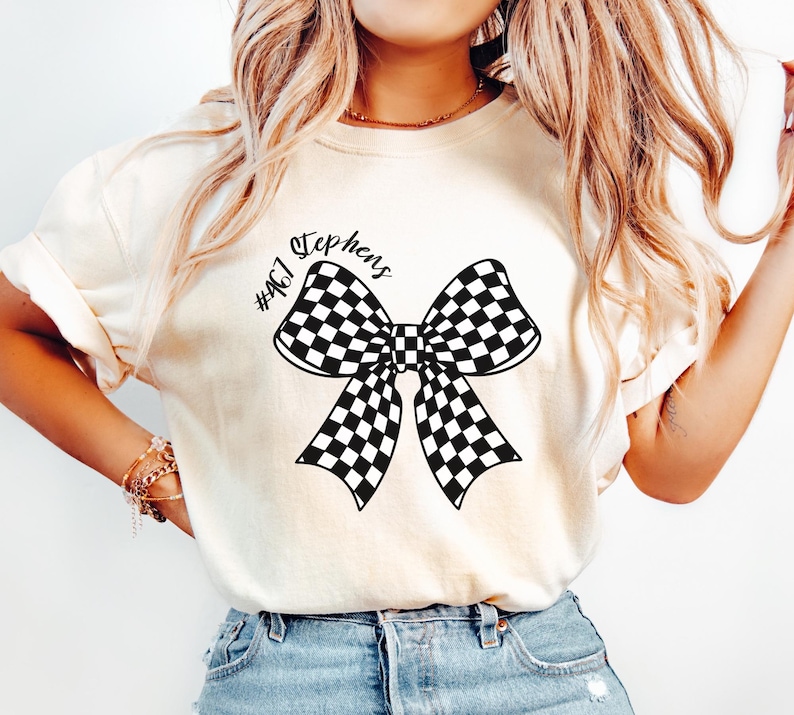 May include: White t-shirt with a black and white checkered bow and the text "#467 Stephens" printed on the front.