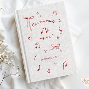 May include: A hardcover book with a light beige linen cover. The cover features red musical notes, hearts, bows, and the text "the songs inside my head" and "BY: ELISABETH ROSE". The book is a journal or notebook.
