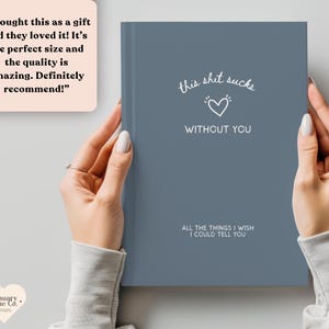 May include: A blue journal with the text "this shit sucks without you" and "All the things I wish I could tell you." The journal is held by a person.