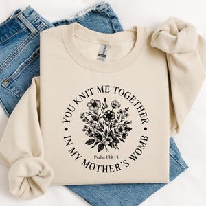 May include: A beige sweatshirt with a black floral design and the text "You knit me together in my mother's womb. Psalm 139:13"