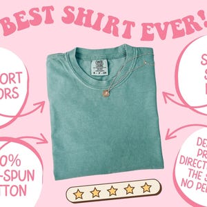 Puede incluir: Una camiseta de color verde azulado con el texto "BEST SHIRT EVER!" en rosa. La camiseta est&aacute; hecha de 100% algod&oacute;n hilado en anillo y tiene un tacto s&uacute;per suave. Un collar de oro con un colgante descansa sobre la camiseta. El dise&ntilde;o est&aacute; impreso directamente en la camiseta.