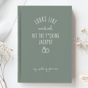 K&ouml;nnte beinhalten: Ein hellgr&uuml;ner Hochzeitsplaner mit wei&szlig;em Text, der "LOOKS LIKE michael HIT THE F*CKING JACKPOT" und "my wedding planner" lautet. Das Cover zeigt auch zwei Eheringe. Der Planer ist ein Hardcover-Buch.