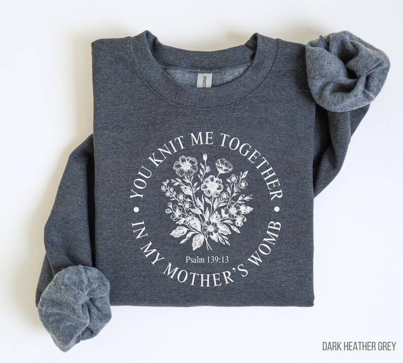 May include: Dark heather grey sweatshirt with a white floral design and the text "You knit me together in my mother's womb" and "Psalm 139:13".