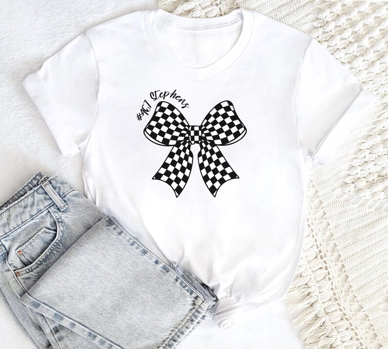 May include: White t-shirt with a black and white checkered bow and the text "#461 Stephens" printed on the front.
