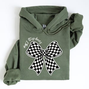 May include: A green hooded sweatshirt with a black and white checkered bow and the text "#467 Stephens" printed on the front.