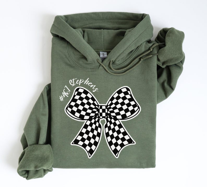 May include: A green hooded sweatshirt with a black and white checkered bow and the text "#467 Stephens" printed on the front.