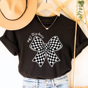 May include: Black t-shirt with a white checkered bow and the text "#467 Stephens" printed on the front.