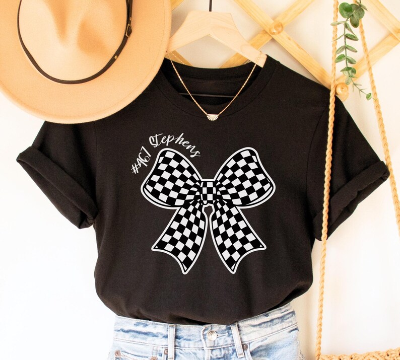 May include: Black t-shirt with a white checkered bow and the text "#467 Stephens" printed on the front.
