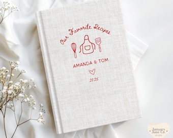 May include: A cream-colored recipe book with the text "Our Favorite Recipes" in red script. The cover features red illustrations of kitchen tools and the names "AMANDA & TOM" with a heart and the year "2025".